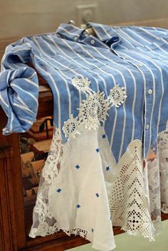 an old fashioned table cloth with blue and white laces on it, hanging from a clothes rack