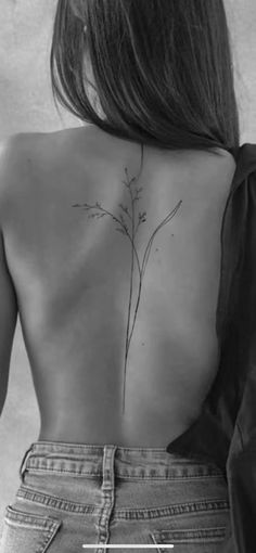 the back of a woman's body with a flower tattoo on her lower back