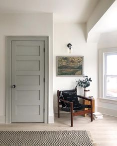 an empty room with a chair, rug and painting on the wall next to it