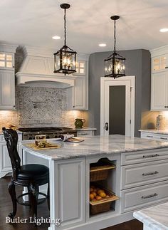 a large kitchen with white cabinets and marble counter tops, two chandeliers hanging from the ceiling