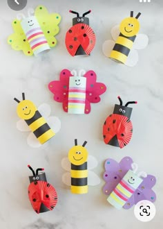 paper crafts made to look like ladybugs and bees on a marble surface with text overlay