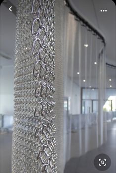 the inside of an office building with white walls and metal chains hanging from the ceiling