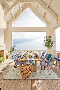 a dining room table with blue chairs and an ocean view in the backround