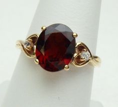 This lovely garnet ring has a nice heart detail on the sides for a little something extra :) The ring features an oval cut garnet that measures 10 x 8 mm. The garnet is a deep red color. The ring also has 2 round cut cubic zirconias that measure 2.00 mm. The hearts on the sides fade into a split look side shank. The ring is stamped 10 kt and weighs 3.1 grams. The ring is a size 7.5. *Sizing is available. Please message us for a quote* *We are always willing to ship Internationally! Please messag Classic Oval Heart Ring For Valentine's Day, Heart-shaped Gemstone Ring For Valentine's Day, Oval Birthstone Ring For Valentine's Day, Classic Heart-shaped Ruby Ring, Side Fade, Deep Red Color, Garnet Ring, Garnet Rings, Yellow Gold Rings