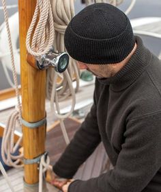 a man sitting on top of a boat next to ropes