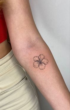 a woman's arm with a small flower tattoo on the left side of her arm