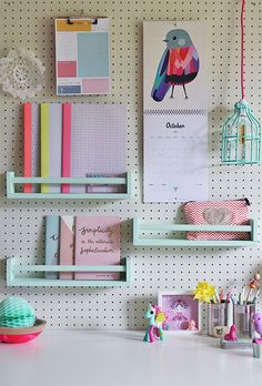 there is a desk with many items on it and a birdcage hanging from the wall