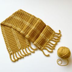 a crocheted scarf next to a ball of yarn