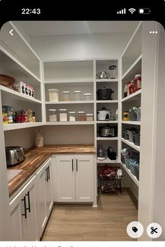 a kitchen with white cabinets and wooden counter tops in the center is an open pantry