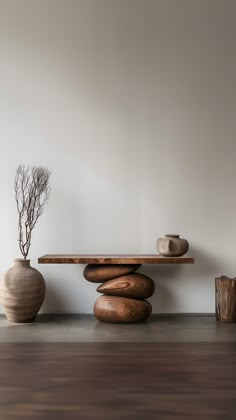 three vases sitting next to each other on top of a wooden table in front of a white wall