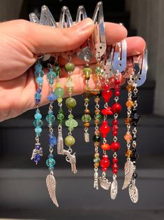 a person holding several different colored beads and charms