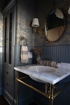 a white sink sitting under a mirror next to a wall mounted faucet in a bathroom