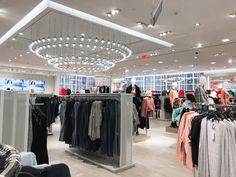 a clothing store with lots of clothes on racks and chandeliers hanging from the ceiling