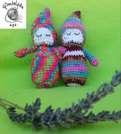 two crocheted stuffed animals sitting next to each other on a green surface with lavender sprigs