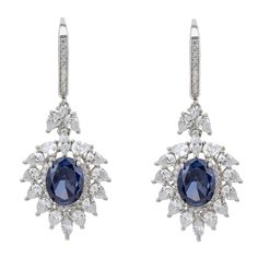 These floral-inspired earrings feature a captivating lab-grown oval tanzanite gemstone at their centre, enveloped by a halo of sparkling simulated diamonds. The design gracefully extends with marquis and teardrop-shaped simulated diamonds, emulating the delicate petals of a blooming flower. Suspended from a hook fastening adorned with additional shimmering stones along its front edge. Perfect for formal events, weddings, or romantic dinners, these earrings add a touch of sophisticated glamour to Tanzanite Drop Earrings, Hyacinth Flower, White Hyacinth, Drop Earrings Silver, August Birthstone Jewelry, July Birthstone Jewelry, Tanzanite Gemstone, Jewelry Ring Box, Pearl Jewellery Earrings