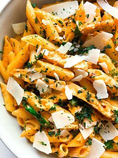 pasta with chicken, parmesan cheese and herbs in a white bowl on a table