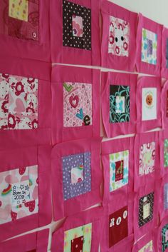 a pink wall hanging with lots of different patchwork designs on it's sides