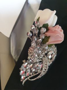 a boutonniere is adorned with crystal beads and pink flowers on a black jacket