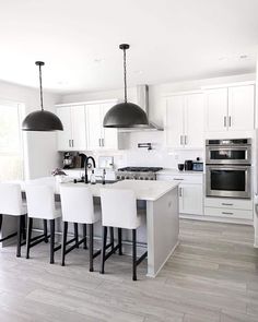 a kitchen with white cabinets and black pendant lights