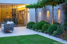 an outdoor living area is lit up with lights and greenery in the foreground