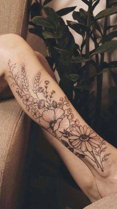 a woman's leg with flowers on it and leaves in the background, while she has