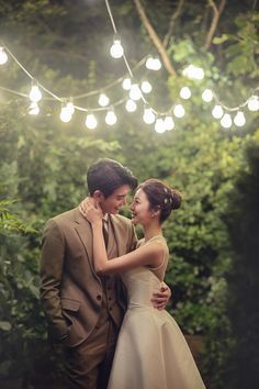 a man and woman standing next to each other under string lights