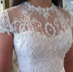 a woman wearing a white wedding dress with lace on it