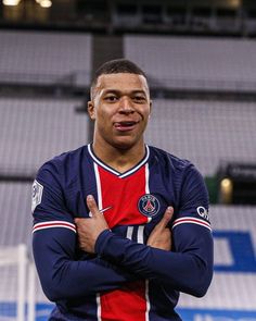 a man standing in front of a soccer field with his arms crossed and looking at the camera