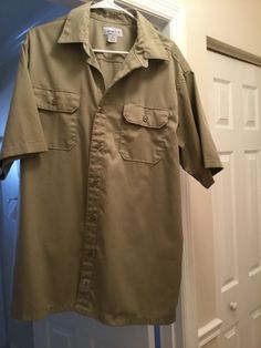 "oversized khaki shirt made by Carharrt.  Label reads that it is poly and cotton, feels like cotton. Size is XL but please see measurements below to ensure a good fit.  Doesn't seem like its been worn much, has that like new feel.  Buttons down front and on pockets, short sleeves.  It's more an olive khaki than a tan khaki, color shows best in pix 1 above.  Only issue to note: a few spots on lower front, near hem, won't show if tucked in.   Measurements:  52\" chest; mid body and hem is 51\"; sh Khaki Shirt, Safari Shirt, Quality Hats, Mens Khakis, Boyfriend Shirt, Olive Color, Khaki Color, Hats Vintage, Boho Hippie