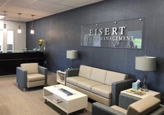 an empty waiting room with couches and tables in front of the reception desk at essert health management