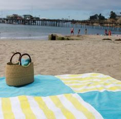 a beach towel with sunglasses on it next to the ocean