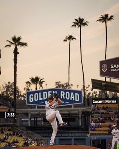 a baseball player pitching a ball on top of a mound in front of palm trees