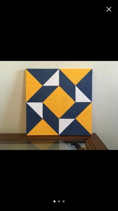 a yellow and blue painting sitting on top of a wooden shelf