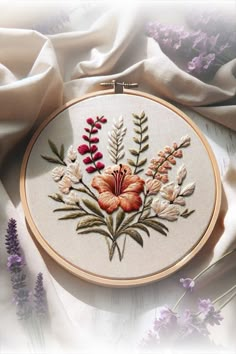 an embroidered flower is shown on a white surface with purple flowers in the foreground