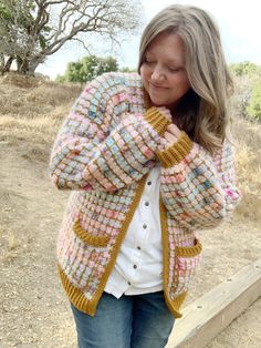 a woman standing on a wooden bench wearing a colorful cardigan