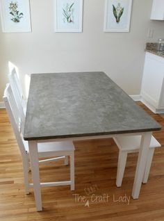 a kitchen table with two white chairs and a gray counter top in front of it