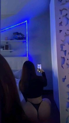 a woman taking a selfie with her cell phone while sitting on the floor in front of a mirror