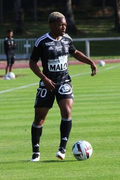 a man standing on top of a soccer field next to a white and black ball