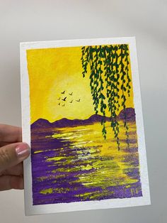 a person holding up a painting with birds flying over the water