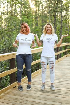 two women standing on a bridge with their hands in the air