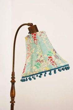 a lamp that is on top of a wooden pole with a flowered fabric shade