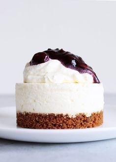 a white plate topped with a cheesecake covered in whipped cream and blueberry topping