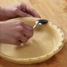 a person using a spoon to make pie crusts