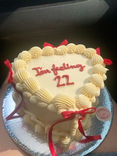 a heart shaped cake with the words i'm feeling 22 on it and red ribbons