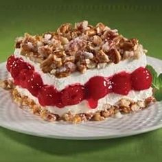 a piece of cake on a white plate with red sauce and walnuts around it