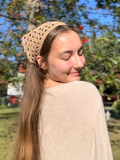 a woman with long hair wearing a knitted headband in front of an apple tree