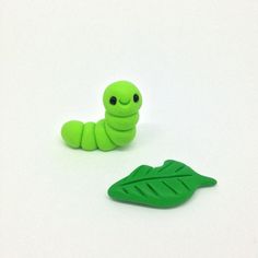 a green caterpillar sitting on top of a leaf next to a smaller one