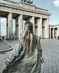 a woman standing in front of a building with columns