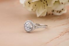 a diamond ring sitting on top of a table next to white flowers and a bouquet