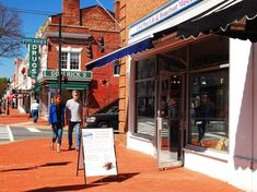 two people walking down the sidewalk in front of a store